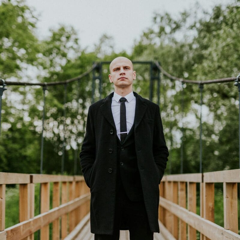Bald Man in Coat on Bridge