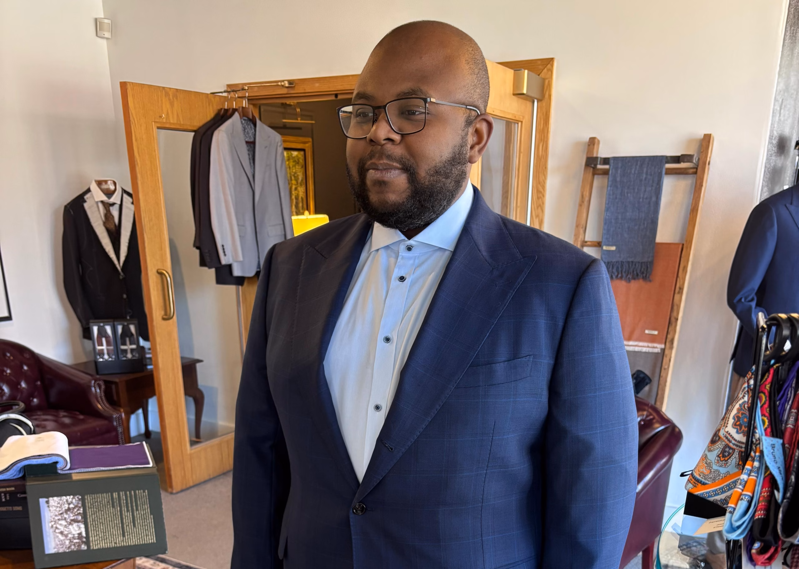 client in navy suit during in-store fitting with fabric swatches visible