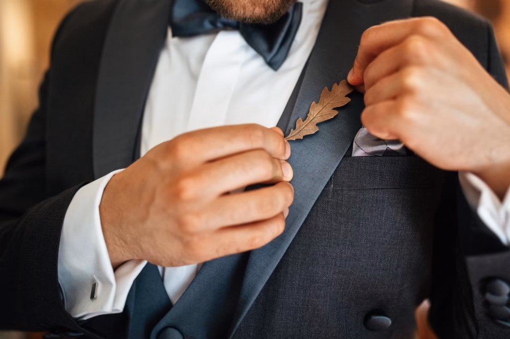 Close up of groom getting dressed with his suit on his wedding day and putting decoration breech