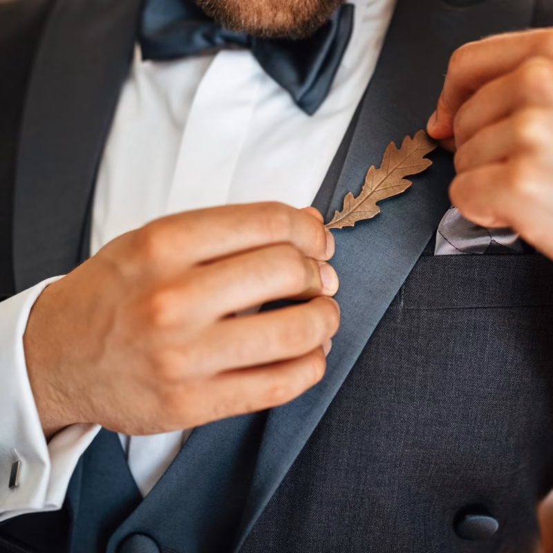 Close up of groom getting dressed with his suit on his wedding day and putting decoration breech
