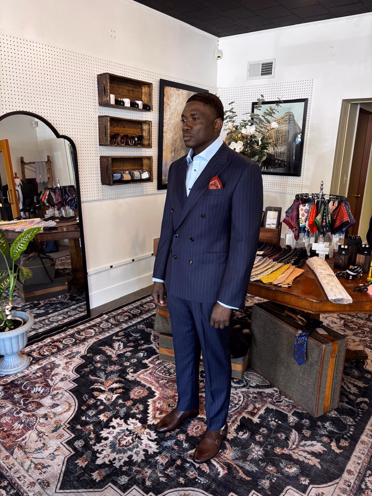 Man wearing a navy pinstripe bespoke suit inside a tailoring studio