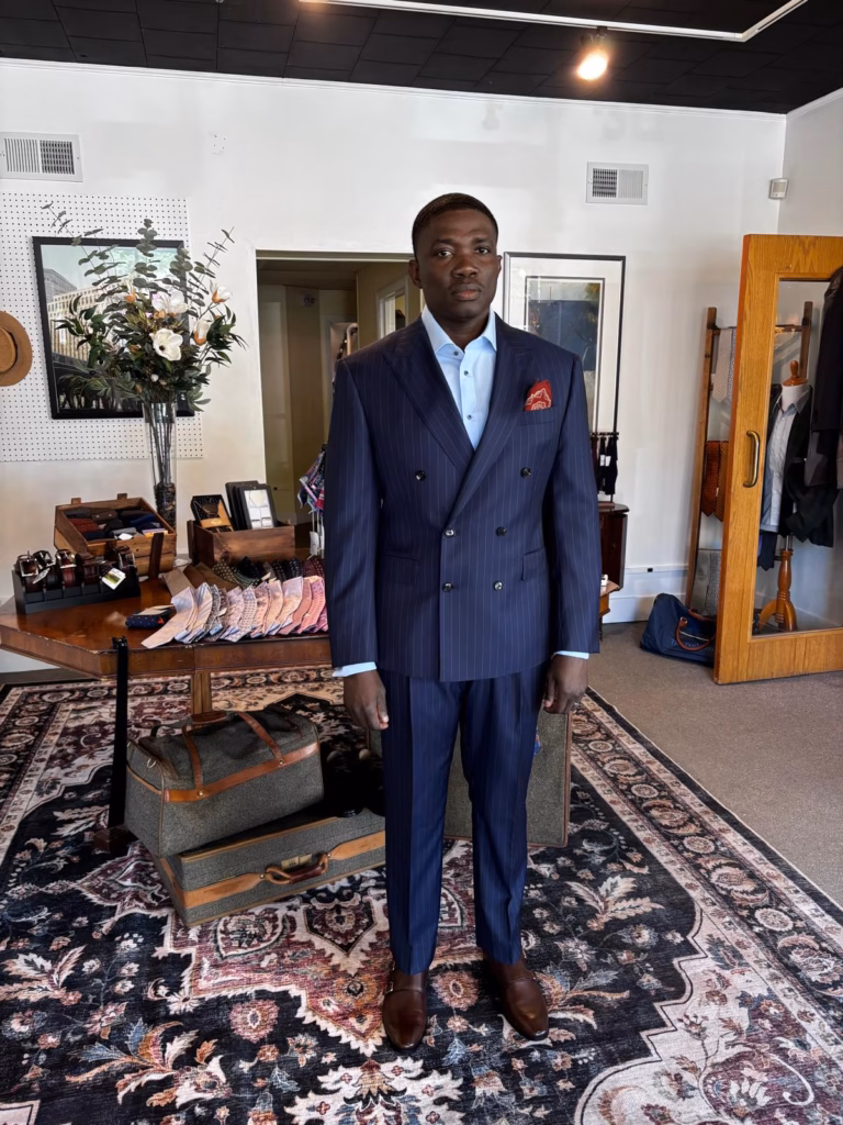 WhatsApp Image 2026-05-22 at 03.53.37 (3) Man wearing a navy pinstripe bespoke suit inside a tailoring studio